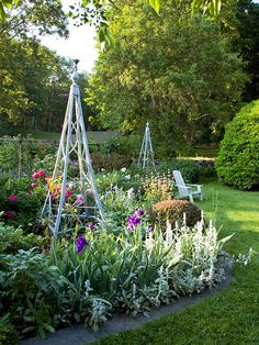 a garden filled with lots of different types of flowers and plants on top of green grass