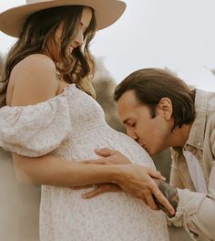 a pregnant woman is touching the belly of a man wearing a cowboy hat and dress