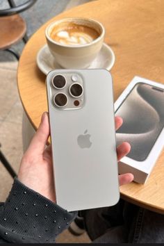 a person holding an iphone in front of a cup of coffee