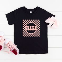 Looking for a cute tee for your kids? We have the perfect Checkered Mini graphic tee addition to their closet! Also available in toddler tees. Cute Black T-shirt With Graphic Design, Cute Black Short Sleeve T-shirt, Playful Streetwear T-shirt With Logo Print, Playful Logo Print T-shirt For Streetwear, Fun Black T-shirt With Graphic Print, Cute Black T-shirt For Summer, Cute Black T-shirt With Text Print, Black Retro T-shirt With Funny Print, Playful Cotton Graphic T-shirt