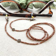 Shiny and bohemian eyeglass necklace chain in copper tones, made with Preciosa Czech crystal seed beads and Hematite  gemstone flower charms.    Paired with delicate copper plated Japanese Miyuki crystal seed beads and copper plated Hematite flower gems, this handmade eyeglass chain will definitely create a unique look. Hematite grounds and protects us. It strengthens our connection with the earth, making us feel safe and secure. It endows us with courage, strength, endurance and vitality. A "st Glasses Necklace, Beaded Sunglasses, Eyeglasses Chain, Sunglasses Necklace, Eyeglass Strap, Patina Earrings, Flower Sunglasses, Eyeglass Necklace, Glasses Chains