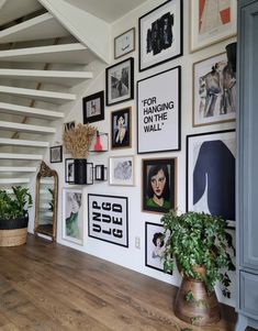 a room with many pictures on the wall and plants in potted planters next to it