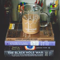 three books stacked on top of each other next to a glass mug filled with liquid