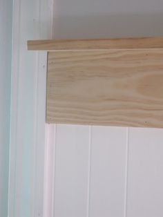 a wooden shelf above a white tiled wall