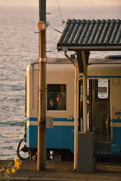 a blue and white train traveling down tracks next to the ocean