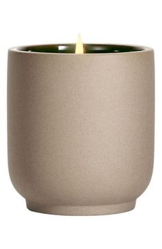 a candle that is sitting inside of a cup on a white surface with a light in the middle