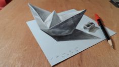 an origami boat is sitting on top of a piece of paper with a pencil