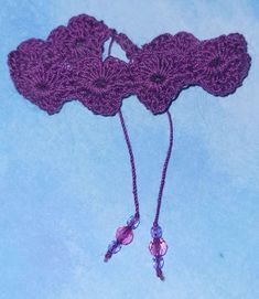 a purple crocheted object on a blue surface with two strings attached to it