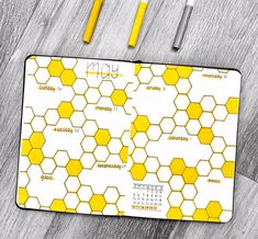 a yellow and white mouse pad sitting on top of a wooden floor next to three pens