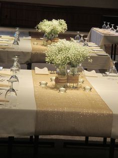 the table is set with white flowers and place settings for guests to sit down at