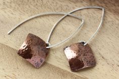 Hand formed sterling silver open hoops in an almond shape with dangling hammered copper squares, in a diamond shape. These light weight copper earrings have a light patina that brings out an earthy warm quality. Modern and a bit rustic! These earring are 1 3/4 inches (4.5 cm) long in the front, the back hangs a bit longer.  The copper square is 5/8 x 5/8 inches (16 mm) All earrings come with clear earring stoppers. All of my designs are created by me, including all the metal components like ear Minimalist Hammered Copper Jewelry, Handmade Modern Copper Jewelry, Modern Handmade Copper Jewelry, Artisan Hammered Rose Gold Jewelry, Artisan Rose Gold Hammered Jewelry, Hoop Silver Earrings, Hammered Copper Earrings, Clear Earrings, Almond Shape