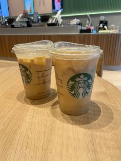 two starbucks drinks sitting on top of a wooden table