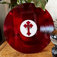 a red plate with a cross on it sitting on a table next to a potted plant