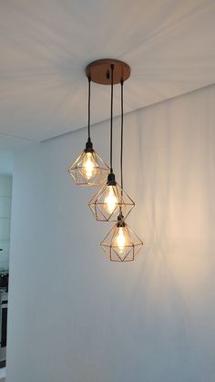 three light fixtures hanging from the ceiling in a room with white walls and flooring