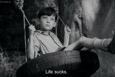 a young boy sitting in a tire swing