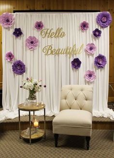 a chair sitting in front of a white curtain with purple flowers on it and the words hello beautiful