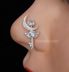 a close up view of a nose piercing with an ornate cross and moon design on it