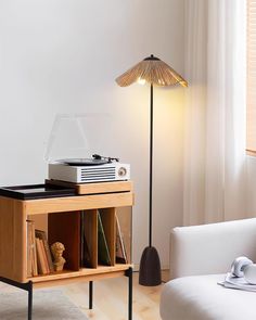 a record player sitting on top of a wooden table next to a white couch and lamp