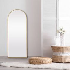 an oval mirror sitting on top of a wooden floor next to a basket and vase