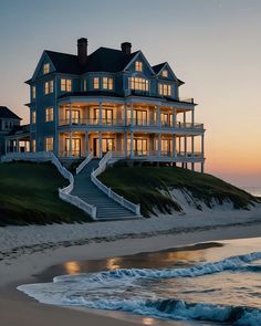 a large house sitting on top of a sandy beach next to the ocean at sunset