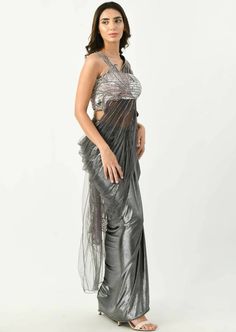 Selena sari is a unique twist to the graceful and the most beloved ethnic attire. The draped sari has fully ornamented blouse in silver. The upper part is embellished with patchwork of lily all over the blouse and pallu. The gun metal color is making this attire to stand out in a crowd and is perfect for any occasion. Diwali Silver Pre-draped Saree With Mirror Work, Bollywood Style Hand Embellished Draped Saree, Bollywood Style Hand Embellished Pre-draped Saree, Festive Hand Embellished Draped Saree, Designer Draped Hand Embellished Saree, Designer Hand Embellished Draped Saree, Glamorous Blouse With Sheer Dupatta In Traditional Drape, Glamorous Blouse With Sheer Dupatta And Traditional Drape, Silver Pre-draped Saree With Zari Work For Festive Occasion