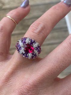 The center stone in this ring is just stunning with deep pink saturation of the stone. . The center piece is a genuine pink tourmaline measuring 7.75mm x 5.75mm, and it has a beautiful checkerboard cut for additional sparkle. The pink tourmaline is accompanied by genuine deep purple amethyst, pale rose amethysts, and additional pink tourmaline round stones.  There are round diamonds totaling approximately .16ctw G/SI1 This ring is super comfortable.  It slides so nicely on the finger and feels v Luxury Multi-stone Pink Gemstones, Luxury Pink Multi-stone Gemstones, Luxury Pink Gemstone With Center Stone, Luxury Oval Ruby Ring With Gemstone, Exquisite Oval Ruby Ring With Center Stone, Luxury Pink Sapphire Ring With Gemstone Accents, Elegant Pink Ruby Gemstones, Luxury Pink Multi-stone Sapphire Ring, Luxury Pink Oval Sapphire Ring