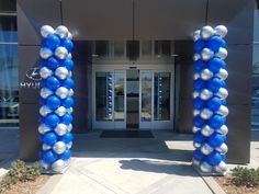 two blue and white balloons are in front of the entrance to a building with an open door