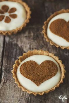 two small pies with some kind of heart on top of them, sitting on a wooden table