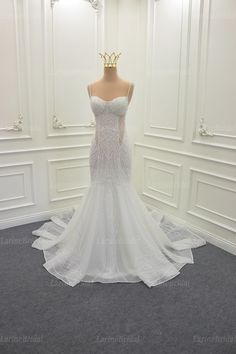 a white wedding dress on display in a room with gray carpet and white paneled walls