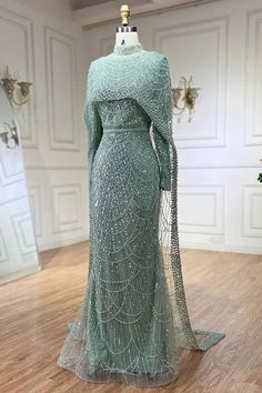 a dress on display in a room with white walls and wooden floors, wearing a green gown