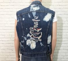 "1980's Levis denim vest. Cut off frayed sleeves with holes and bleach splashes throughout. Non-bulky fit. Dual front chest patch pockets with buttoned flaps. Perfect for adding your own patches + pins to. ✂ Measurements ✂ Labelled size: 45 Fits like: Mens 45 / Medium To Large depending on desired fit // Ladies Large ✂ Measurements: ( taken laying flat and buttoned ) Shoulders: 19.5\" Length: 24.25\" Chest: 22.5\" Waist: 21.25\" Waistband: 20.5\" Label + Fabric Levis Made in U.S.A 100% Cotton Co Edgy Cotton Denim Vest For Summer, Fitted Grunge Vest For Festivals, Grunge Sleeveless Vest For Spring, Sleeveless Grunge Vest For Spring, Spring Sleeveless Grunge Vest, Spring Grunge Sleeveless Vest, Fitted Grunge Vest For Fall, Distressed Medium Wash Denim Vest For Summer, Medium Wash Distressed Denim Vest For Summer