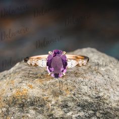 an amethoraite and diamond ring sitting on top of a rock