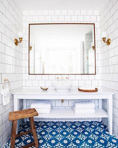 a bathroom with blue and white flooring and a large mirror above the bathtub