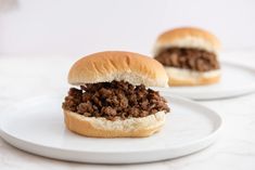 two white plates with sloppy joe sandwiches on them