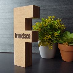 a wooden block that says francisco next to a potted plant