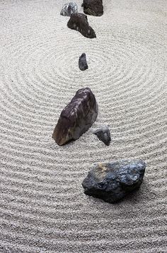 some rocks and sand in a circular pattern on a white surface with black dots around them