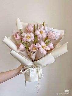 a person holding a bouquet of pink flowers