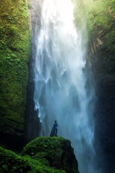 a person standing at the base of a waterfall