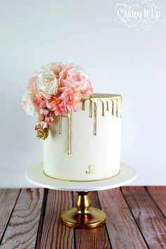 a white cake topped with pink flowers on top of a wooden table