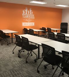 an empty classroom with desks and chairs in front of the wall that says teamwork