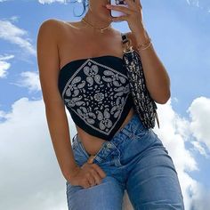 a woman is taking a selfie with her cell phone while wearing jeans and a bandana