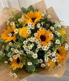 a bouquet of sunflowers and daisies in brown paper