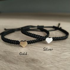 two bracelets with hearts on them sitting on top of a wooden table next to each other