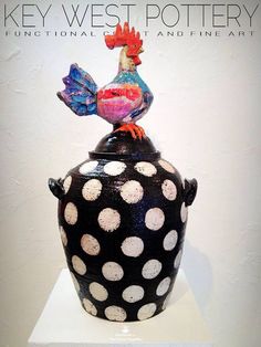 a black vase with white polka dots and a rooster on top