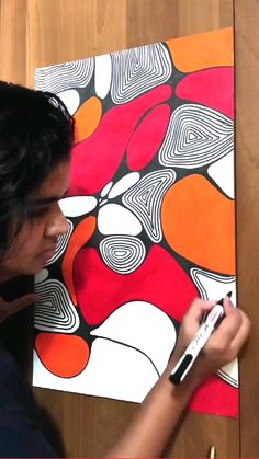 a man is drawing on a piece of art with marker and pen in his hand