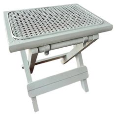 a white plastic table with two legs and a tray on the top that has holes in it