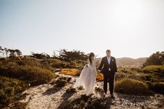 a bride and groom walking down a path in the desert with sun shining on them