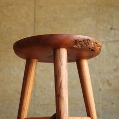 a wooden stool sitting in front of a wall