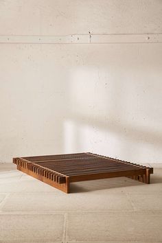 a wooden bed frame sitting on top of a tile floor next to a white wall