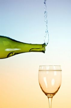 a wine glass is being filled with water from a bottle into a goblet